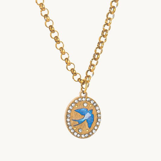 Homeward Swallow Necklace, an oval gold-tone pendant with a blue enamel swallow