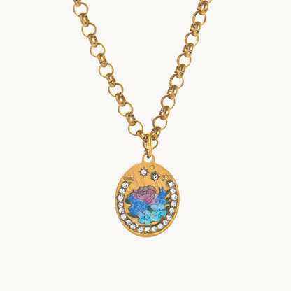 Midnight Rose Necklace, an oval gold-tone pendant with a blue and violet enamel rose